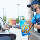 Auntie Anne's employee hands food and beverages to customer in their car at the drive-thru